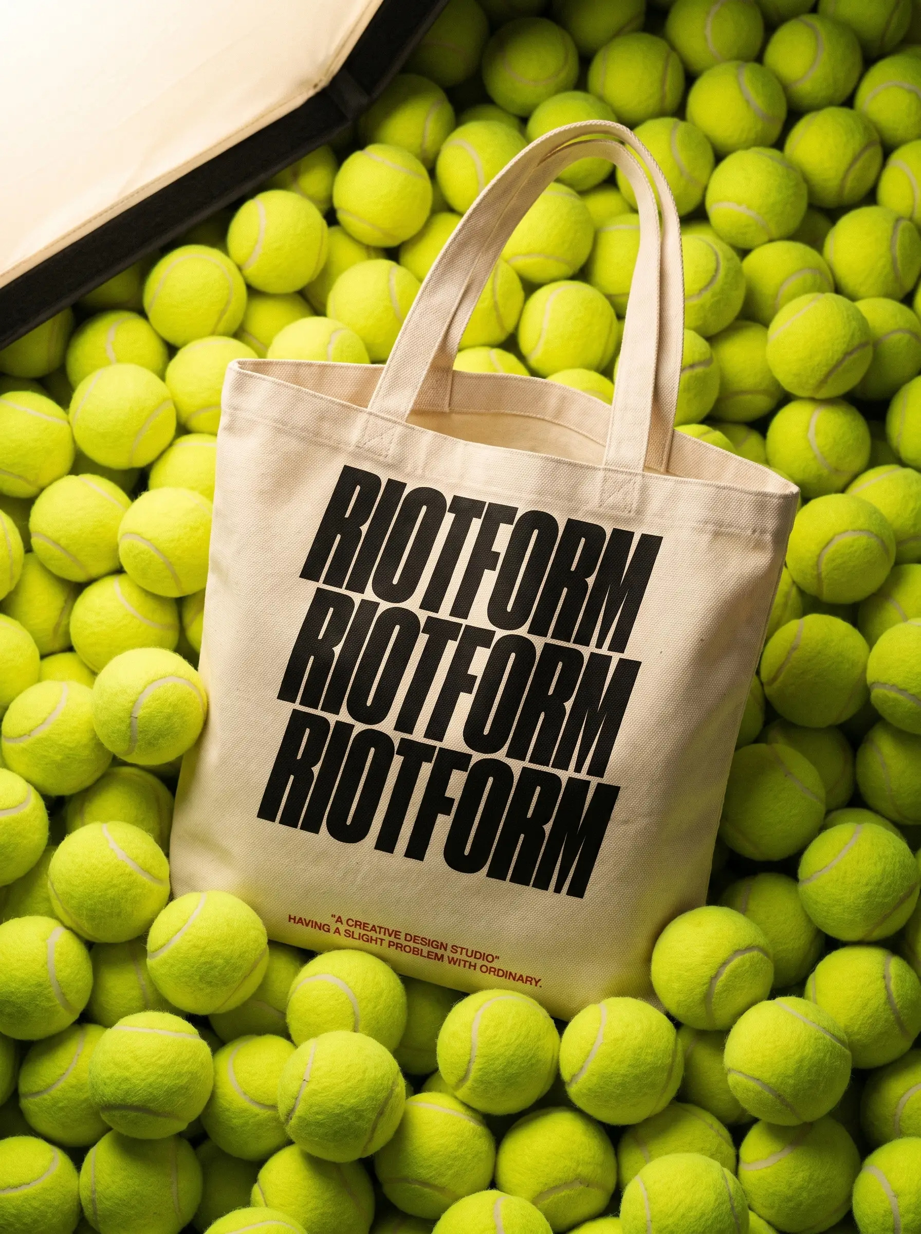 The Riot-Tote lying on a bed of tennis balls, RIOTFORM stacked three times in black